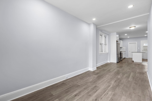 spare room featuring recessed lighting, baseboards, and dark wood-type flooring