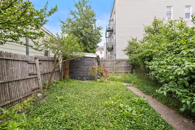 view of yard featuring an outbuilding, a storage unit, and a fenced backyard