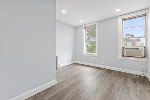 spare room featuring wood finished floors, radiator heating unit, recessed lighting, cooling unit, and baseboards