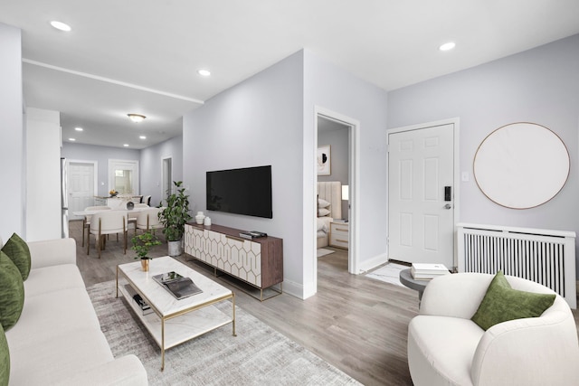 living area with recessed lighting, baseboards, radiator, and light wood-style flooring