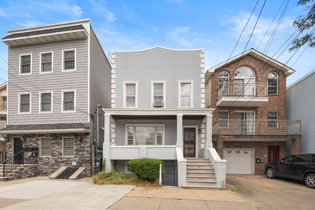 view of front facade with a balcony, driveway, an attached garage, stucco siding, and brick siding