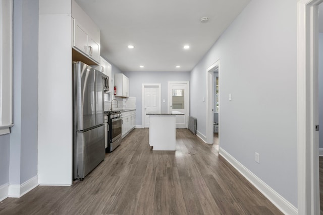 kitchen with a center island, decorative backsplash, appliances with stainless steel finishes, white cabinetry, and a sink