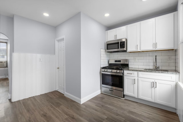 kitchen featuring dark wood-style floors, stone counters, a sink, stainless steel appliances, and white cabinets