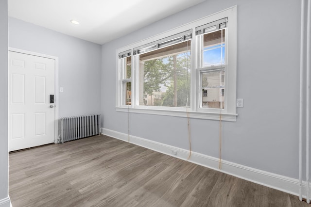 unfurnished room featuring recessed lighting, radiator, baseboards, and wood finished floors