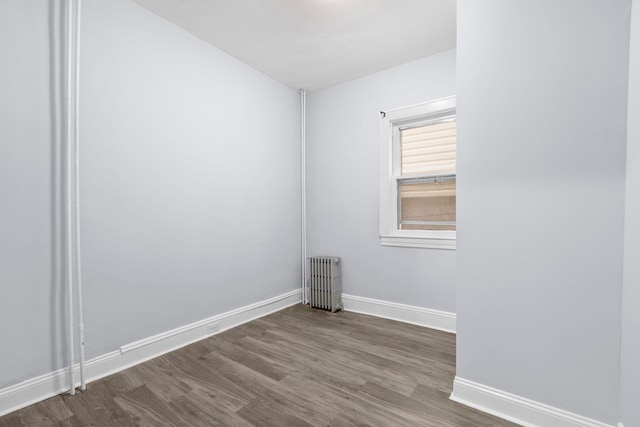 unfurnished room with baseboards, dark wood-type flooring, and radiator