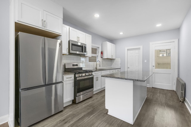 kitchen featuring a sink, a center island, white cabinetry, radiator, and appliances with stainless steel finishes