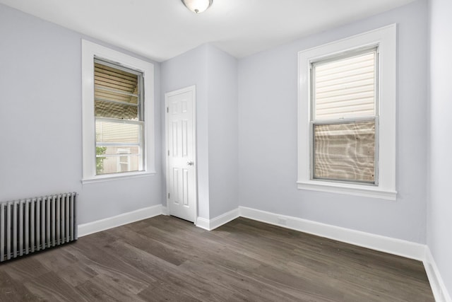 empty room with baseboards, dark wood-style flooring, and radiator heating unit