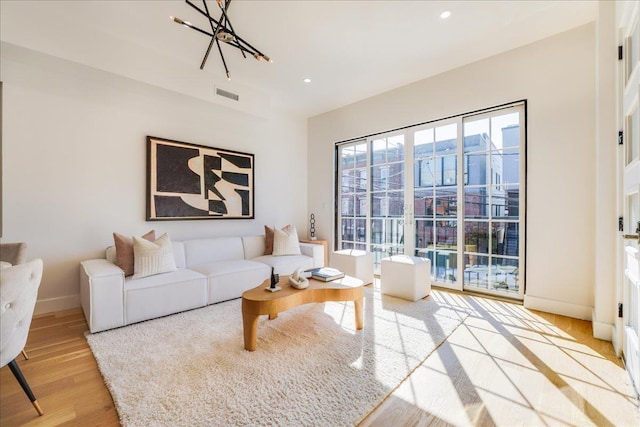 living area featuring light wood finished floors, baseboards, visible vents, a notable chandelier, and recessed lighting