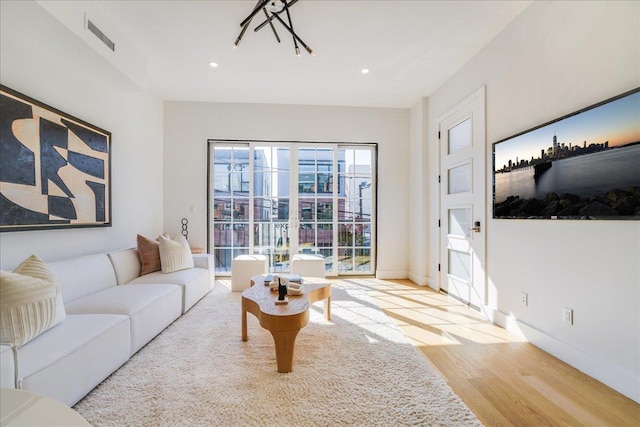 living room featuring visible vents, baseboards, wood finished floors, and recessed lighting