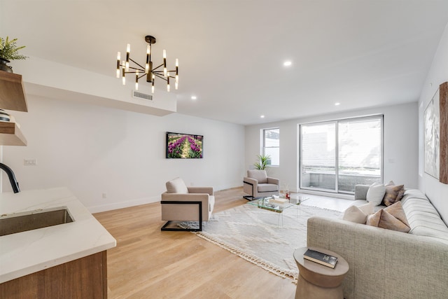 living area with baseboards, visible vents, light wood-style flooring, a notable chandelier, and recessed lighting