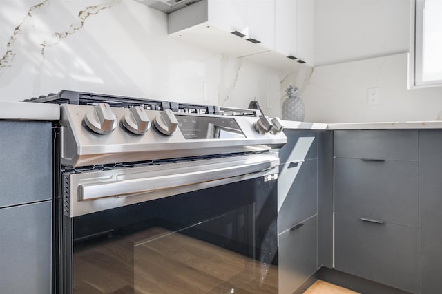 interior details featuring modern cabinets, backsplash, gray cabinetry, gas stove, and wood finished floors