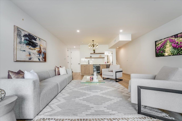 living room featuring indoor bar, wine cooler, light wood-type flooring, a notable chandelier, and recessed lighting