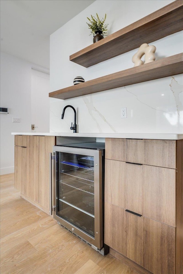 bar with light wood finished floors and beverage cooler