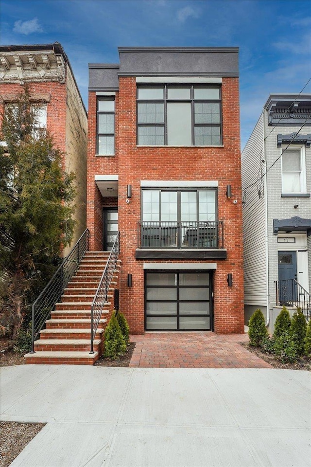 view of front facade featuring an attached garage, stairway, decorative driveway, and brick siding