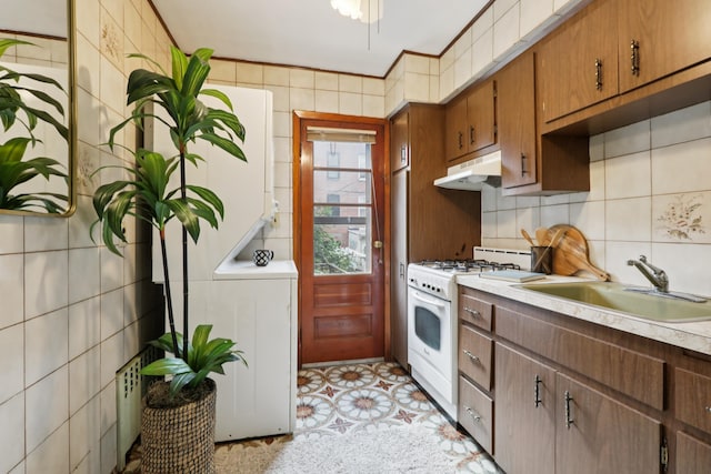 914 Washington St, Hoboken, NJ 07030 - kitchen featuring white gas stove, under cabinet range hood, light countertops, backsplash, and washer / clothes dryer