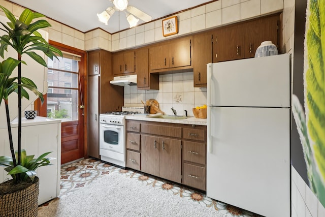 914 Washington St, Hoboken, NJ 07030 - kitchen with white appliances, under cabinet range hood, light countertops, tasteful backsplash, and brown cabinetry
