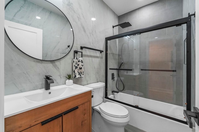 bathroom featuring combined bath / shower with glass door, tile walls, toilet, and vanity