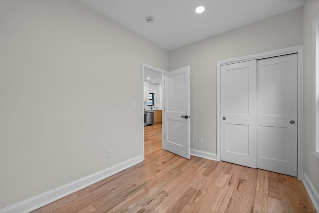 unfurnished bedroom featuring a closet, baseboards, light wood-style floors, and recessed lighting