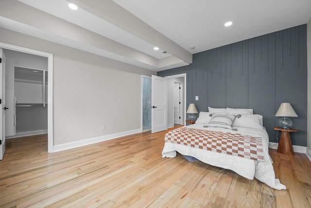 bedroom featuring light wood finished floors, baseboards, a spacious closet, and recessed lighting
