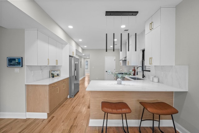 kitchen featuring light countertops, a kitchen bar, a sink, and high quality fridge