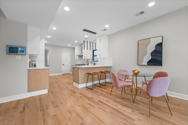 kitchen with light countertops, light wood-style flooring, visible vents, white cabinets, and a peninsula