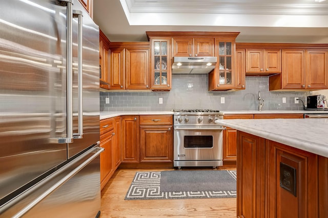 215 Monroe St Unit 3, Hoboken, NJ 07030 - kitchen with premium appliances, under cabinet range hood, light countertops, crown molding, and brown cabinets