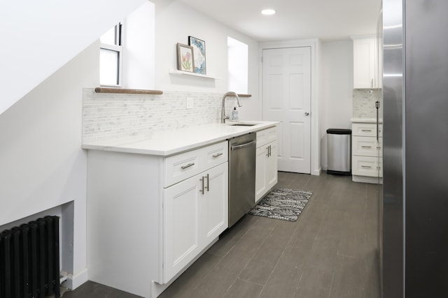 kitchen featuring dark wood finished floors, white cabinets, radiator, stainless steel appliances, and a sink