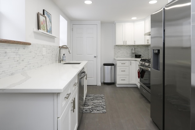 kitchen with under cabinet range hood, dark wood-style flooring, a sink, white cabinetry, and appliances with stainless steel finishes