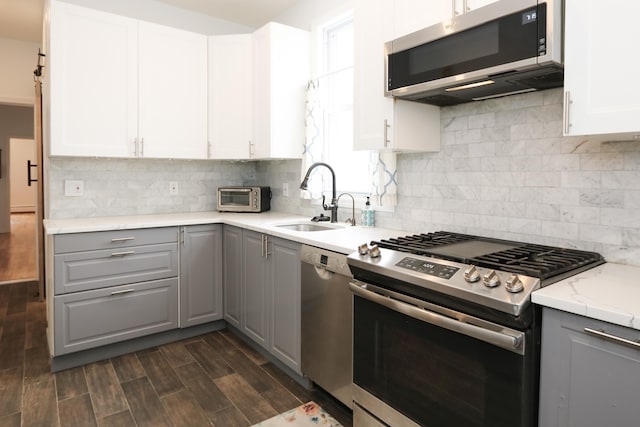 kitchen featuring a toaster, gray cabinets, appliances with stainless steel finishes, wood tiled floor, and a sink