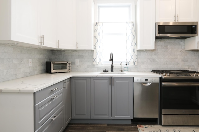 kitchen with gray cabinetry, a toaster, a sink, white cabinets, and appliances with stainless steel finishes