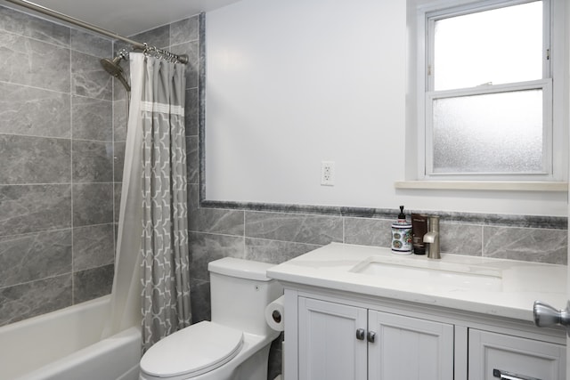 full bathroom featuring toilet, tile walls, shower / bath combination with curtain, and vanity