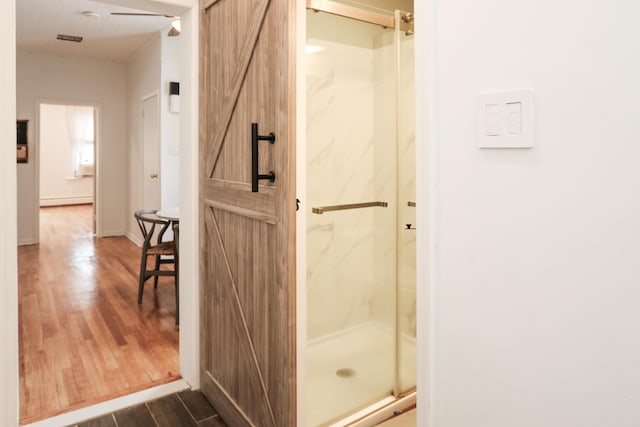 bathroom with a marble finish shower and wood finished floors