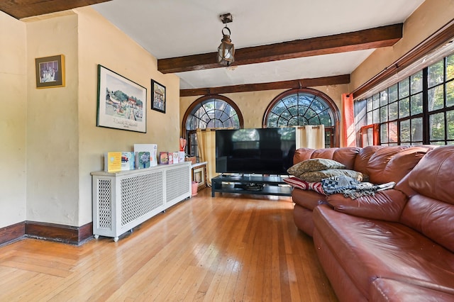 living room featuring beamed ceiling and light hardwood / wood-style flooring