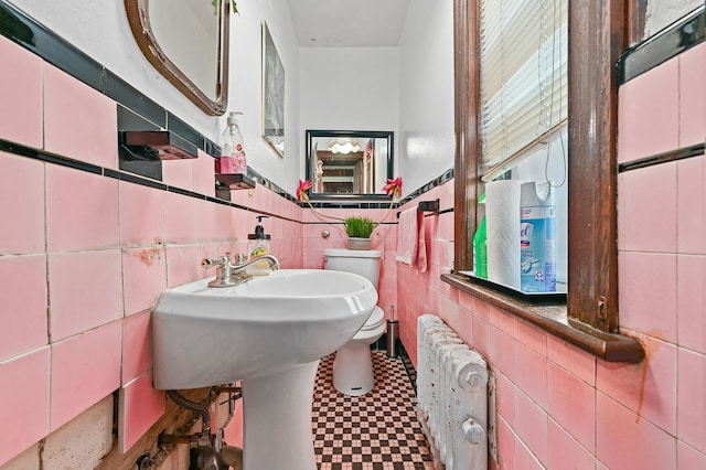 bathroom featuring toilet, radiator, and tile walls