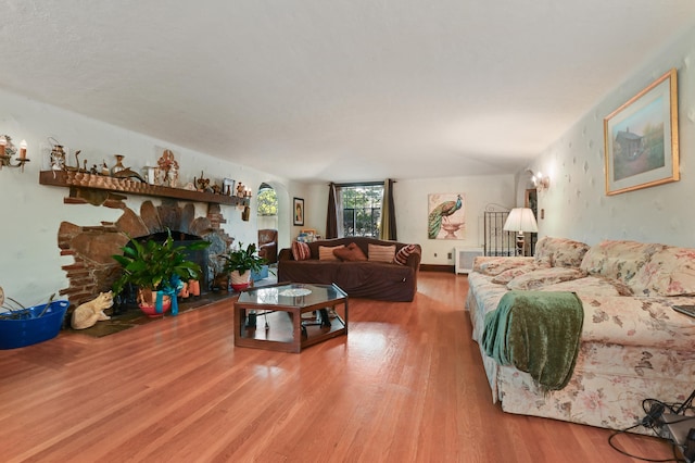 living room with hardwood / wood-style floors and a stone fireplace