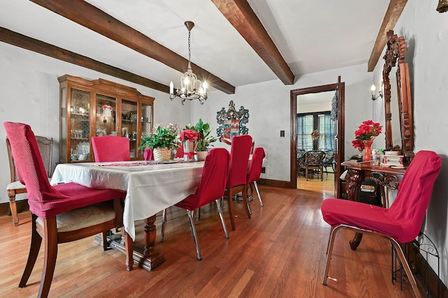 dining area with hardwood / wood-style flooring, beamed ceiling, and an inviting chandelier