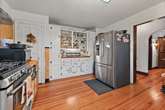 kitchen with white cabinetry, exhaust hood, light hardwood / wood-style floors, and stainless steel appliances