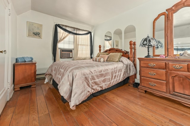 bedroom with a baseboard heating unit, dark hardwood / wood-style flooring, cooling unit, and vaulted ceiling