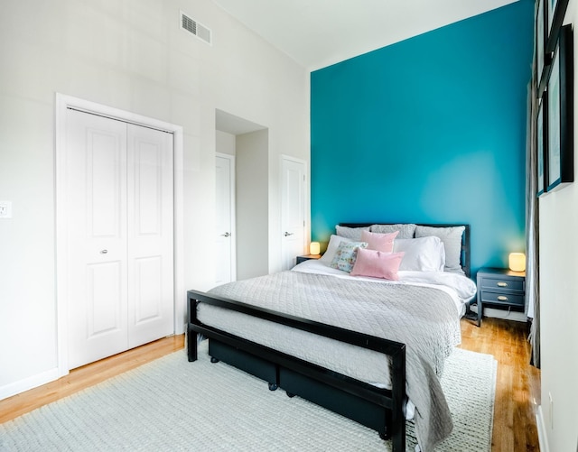 bedroom with wood finished floors, a high ceiling, a closet, and baseboards