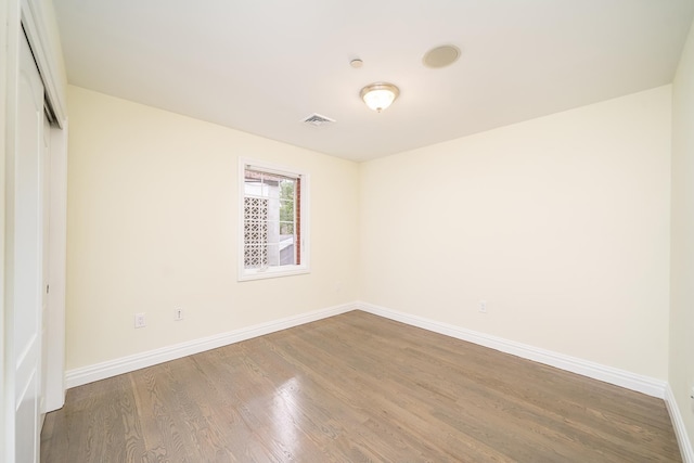 empty room featuring visible vents, baseboards, and wood finished floors