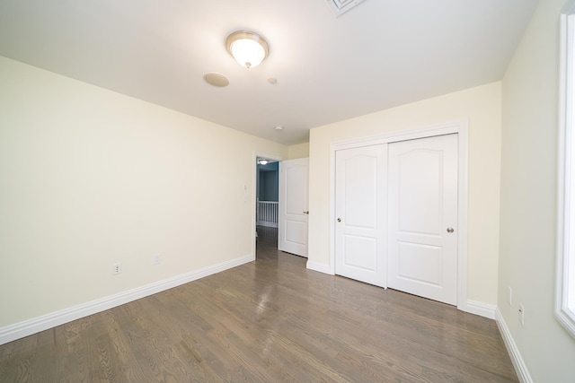 unfurnished bedroom featuring a closet, baseboards, and wood finished floors