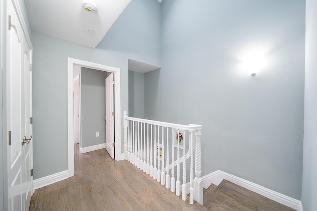 hall with an upstairs landing, baseboards, and wood finished floors