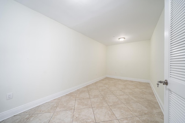 spare room featuring light tile patterned floors and baseboards