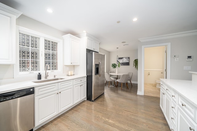 kitchen with a sink, white cabinetry, recessed lighting, stainless steel appliances, and light wood finished floors