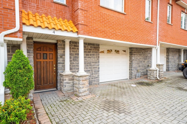 property entrance featuring decorative driveway and an attached garage