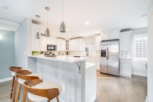 kitchen featuring appliances with stainless steel finishes, a breakfast bar area, light wood-type flooring, and a peninsula