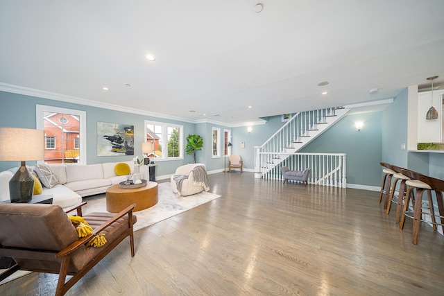 living room featuring stairway, baseboards, wood finished floors, and ornamental molding