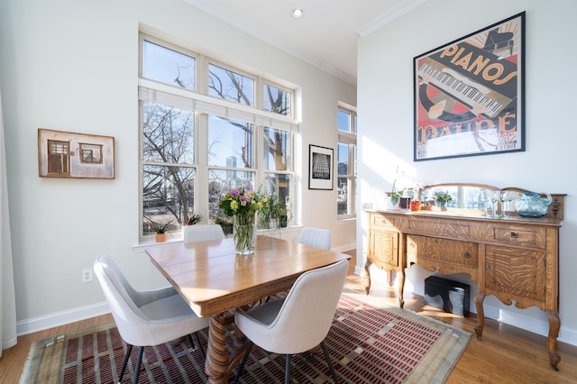 dining space featuring wood finished floors, baseboards, and ornamental molding