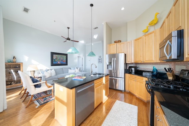 kitchen with light brown cabinets, light wood finished floors, a sink, stainless steel appliances, and dark countertops