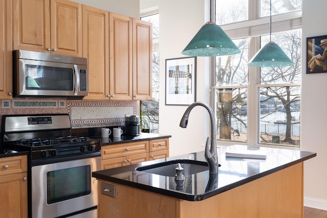 kitchen with an island with sink, a sink, decorative backsplash, light brown cabinetry, and stainless steel appliances